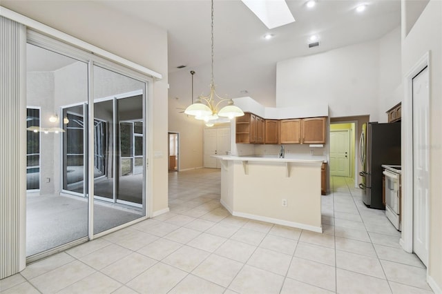 kitchen featuring a skylight, a kitchen bar, white range with electric stovetop, high vaulted ceiling, and pendant lighting