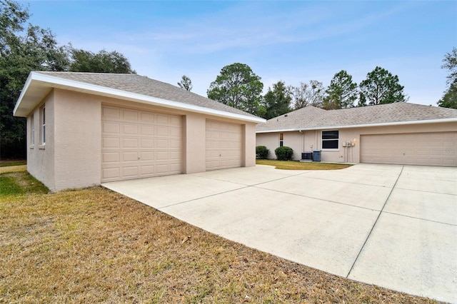 view of front facade featuring a garage, a front lawn, and central AC