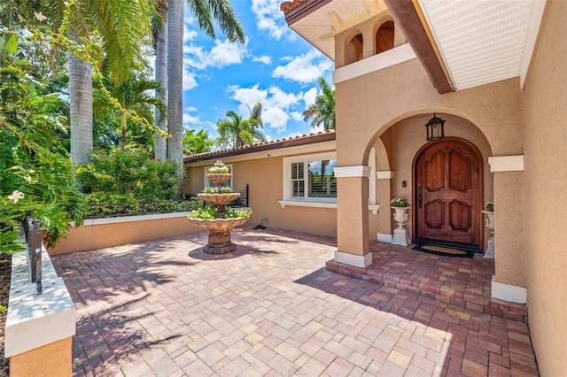 doorway to property featuring a tile roof and stucco siding