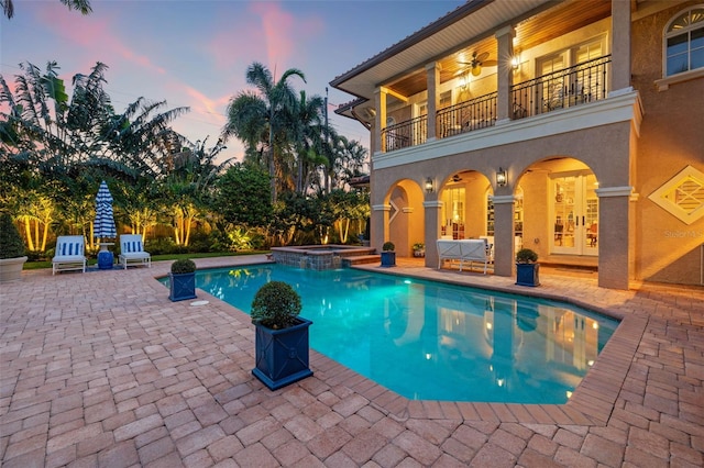 view of swimming pool featuring a pool with connected hot tub, french doors, a patio, and ceiling fan