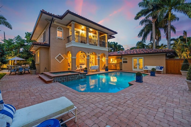 rear view of house featuring a balcony, fence, french doors, stucco siding, and a patio area