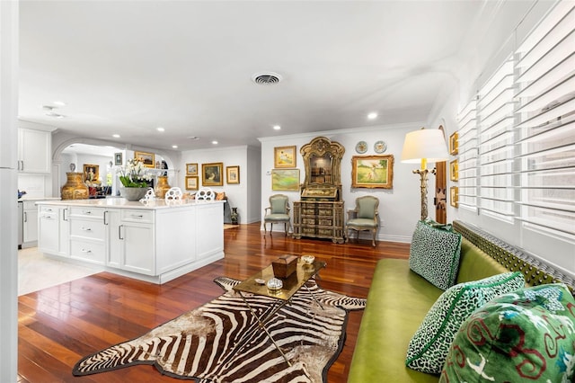 living area with baseboards, light wood-style flooring, visible vents, and crown molding