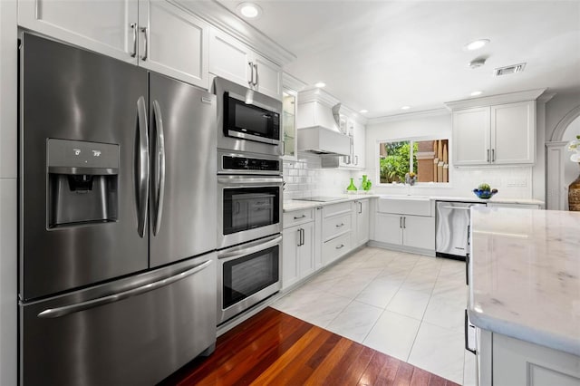 kitchen with visible vents, white cabinets, appliances with stainless steel finishes, a sink, and backsplash