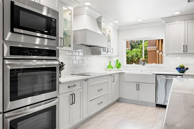 kitchen with appliances with stainless steel finishes, a sink, glass insert cabinets, and white cabinets