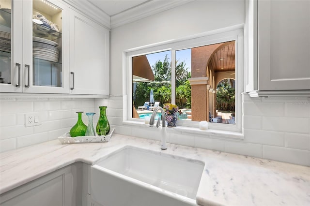 kitchen with tasteful backsplash, a sink, glass insert cabinets, and white cabinets