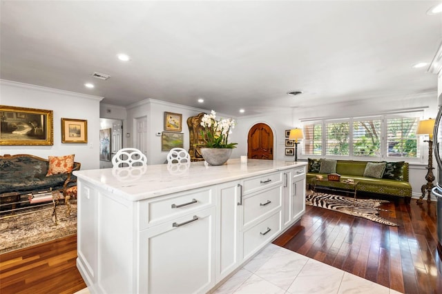 kitchen featuring open floor plan, a center island, visible vents, and white cabinets