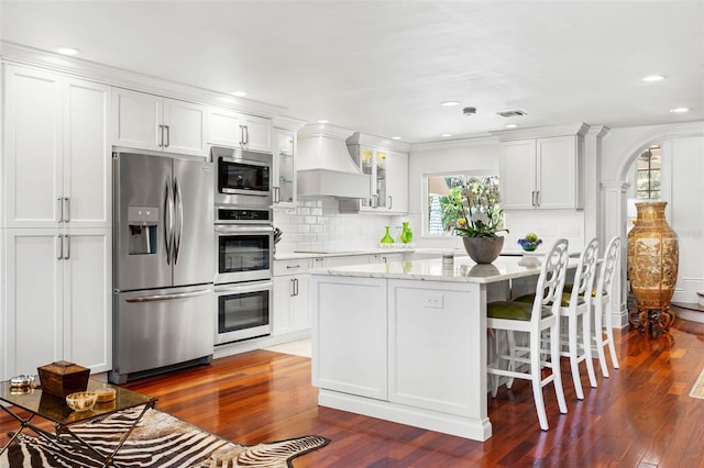 kitchen with appliances with stainless steel finishes, custom exhaust hood, glass insert cabinets, and white cabinets