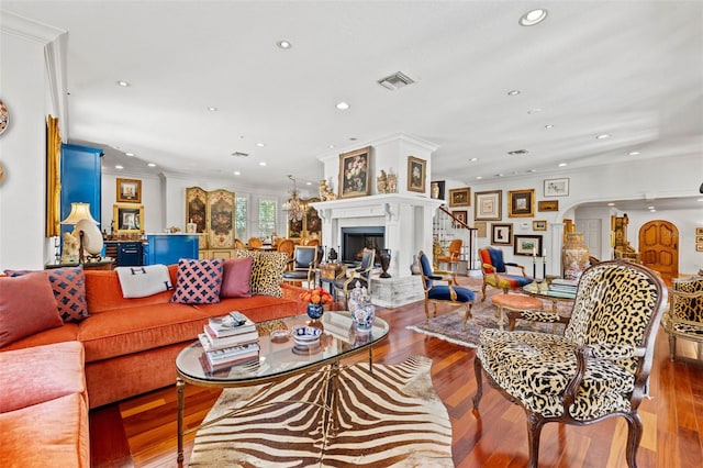 living area with light wood finished floors, visible vents, arched walkways, a premium fireplace, and recessed lighting