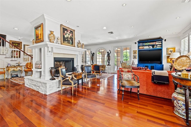 living room with ornamental molding, french doors, a fireplace, and wood finished floors