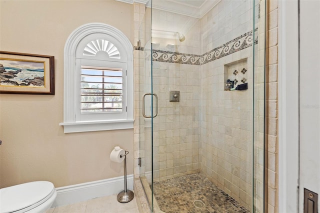 bathroom with crown molding, toilet, a stall shower, tile patterned flooring, and baseboards