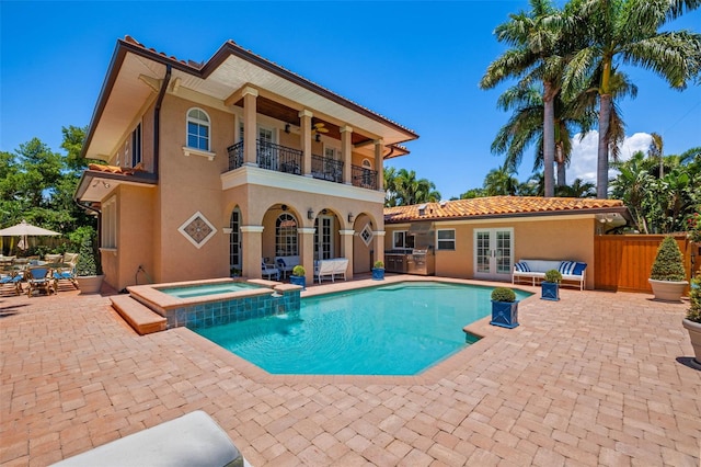 rear view of house with a balcony, fence, french doors, a patio area, and stucco siding