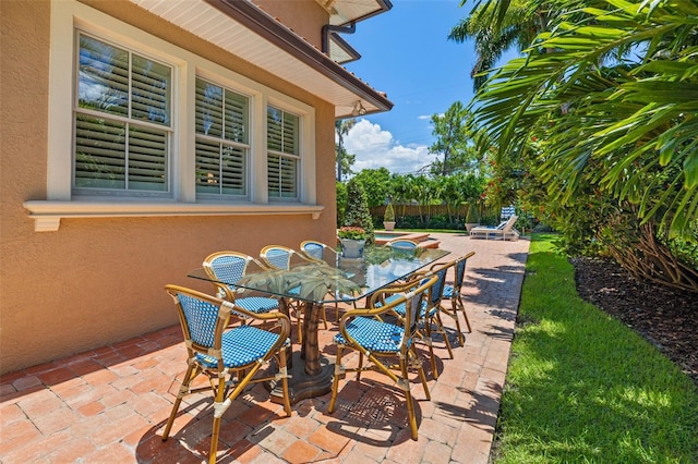 view of patio featuring an in ground hot tub, outdoor dining space, and fence