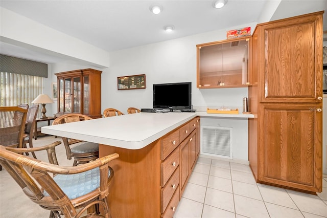 kitchen featuring a kitchen breakfast bar, light tile patterned floors, and kitchen peninsula