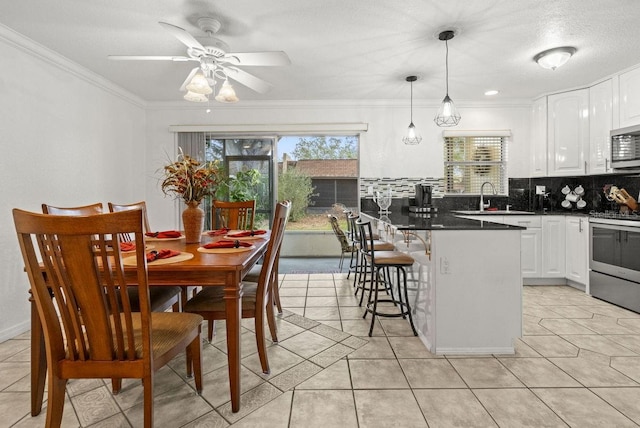 kitchen with a kitchen bar, stainless steel appliances, decorative light fixtures, white cabinets, and sink