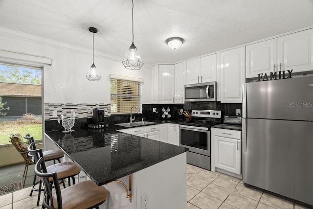 kitchen featuring pendant lighting, appliances with stainless steel finishes, white cabinets, sink, and a breakfast bar area