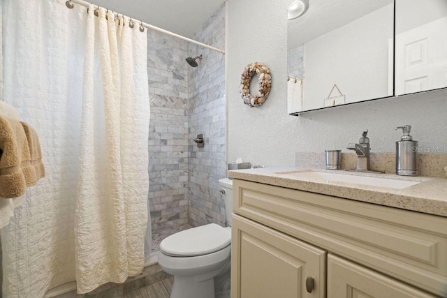 bathroom featuring walk in shower, vanity, toilet, and a textured ceiling