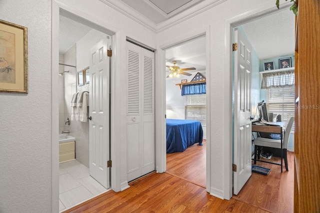 hall with wood-type flooring, crown molding, and a textured ceiling