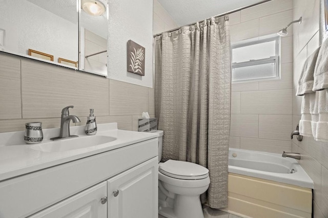 full bathroom with tile walls, vanity, a textured ceiling, and shower / bathtub combination with curtain