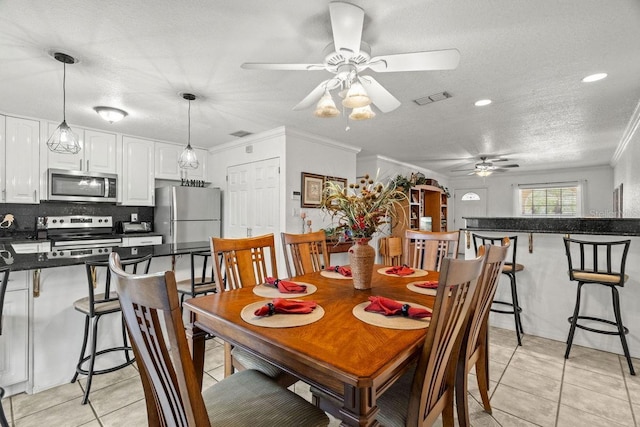 tiled dining area featuring a textured ceiling, ceiling fan, and crown molding