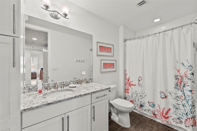 bathroom with curtained shower, toilet, and vanity