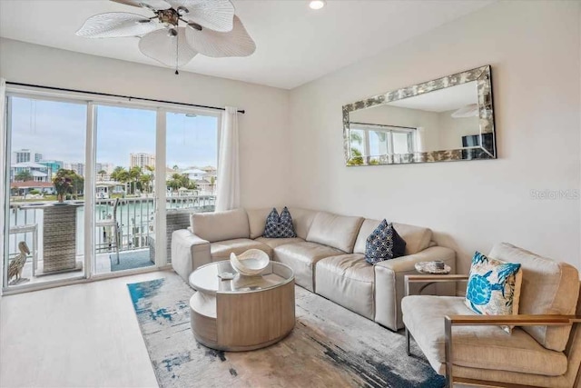 living room with ceiling fan and a water view