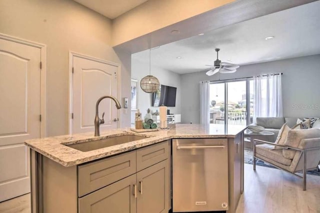 kitchen with light stone countertops, sink, a kitchen island with sink, ceiling fan, and stainless steel dishwasher