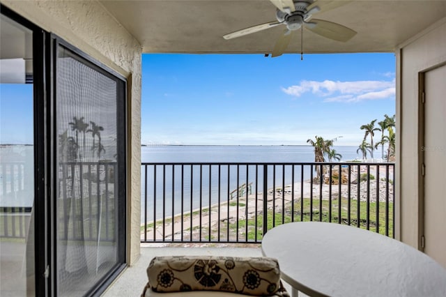 balcony featuring ceiling fan, a water view, and a view of the beach