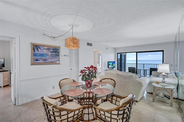 dining area featuring light tile patterned floors and a textured ceiling