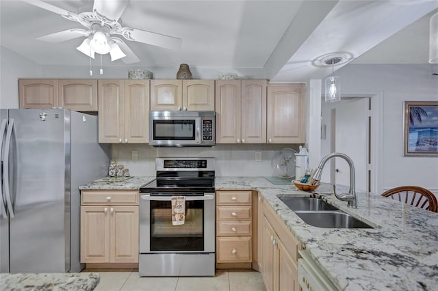 kitchen featuring appliances with stainless steel finishes, sink, light brown cabinets, and decorative light fixtures