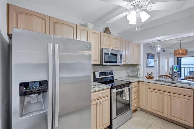 kitchen featuring stainless steel appliances, light brown cabinetry, sink, and light stone countertops