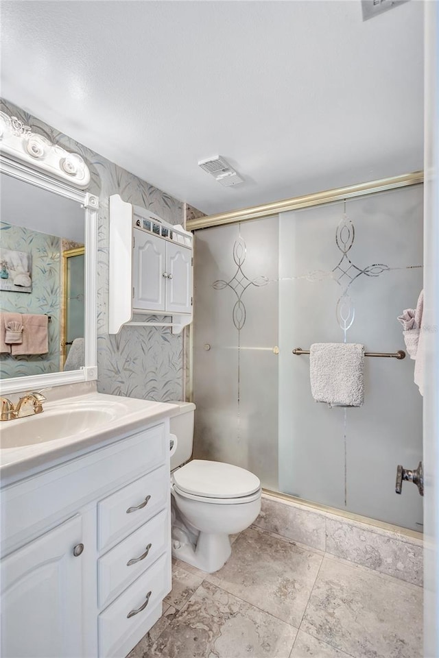 bathroom with vanity, a shower with door, and toilet