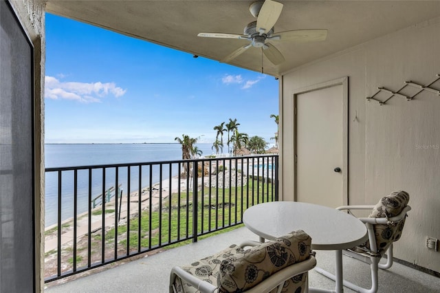 balcony featuring a beach view, ceiling fan, and a water view