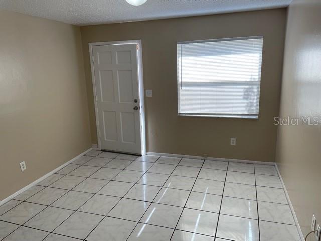 tiled spare room featuring a textured ceiling