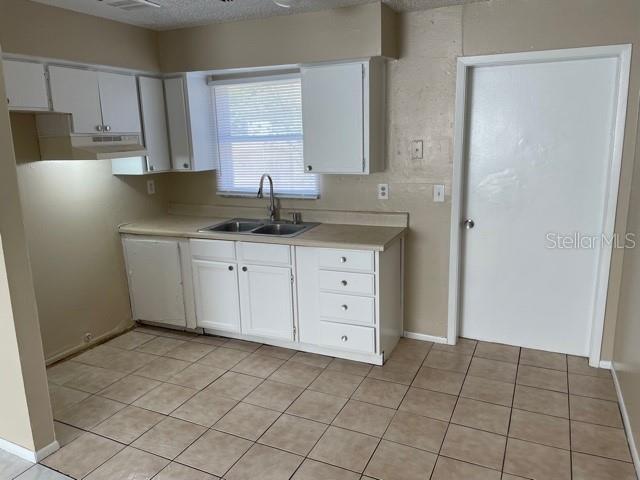 kitchen featuring light tile patterned floors, sink, a textured ceiling, and white cabinets