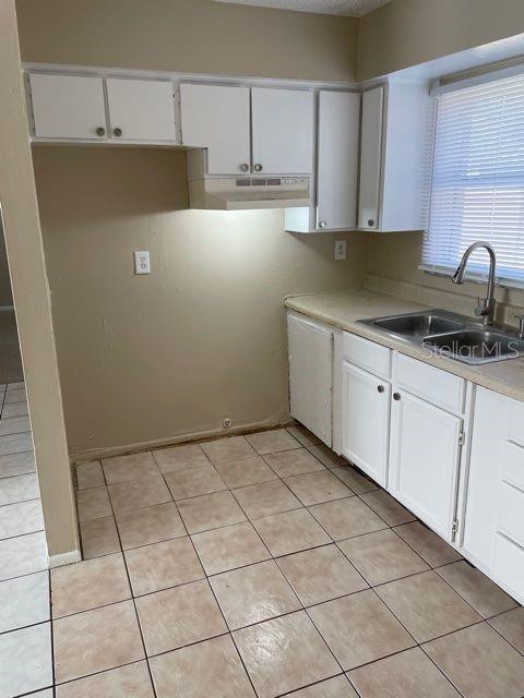 kitchen with light tile patterned floors, sink, and white cabinets