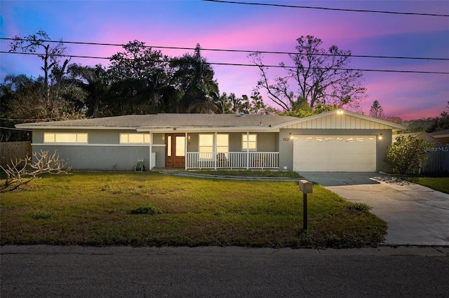 single story home with a yard, a garage, and a porch