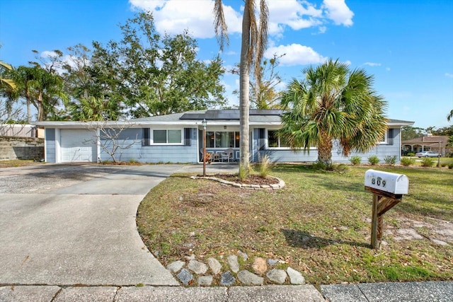 ranch-style house with a garage, solar panels, and a front lawn