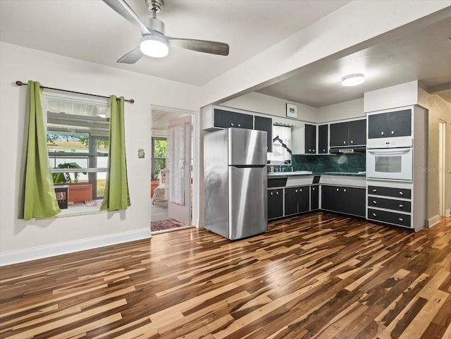 kitchen featuring sink, dark wood-type flooring, stainless steel fridge, and oven