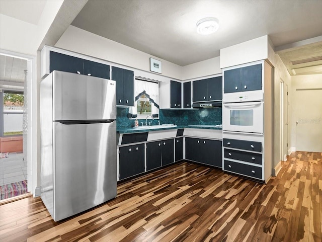 kitchen with dark wood-type flooring, stainless steel refrigerator, a healthy amount of sunlight, and white oven