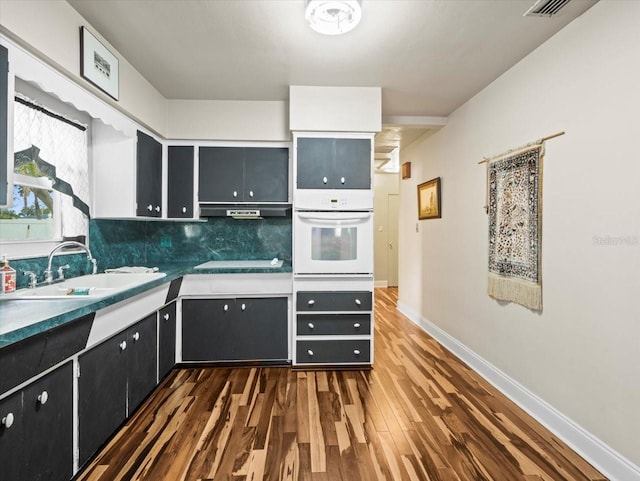 kitchen featuring sink, backsplash, dark hardwood / wood-style floors, electric cooktop, and oven