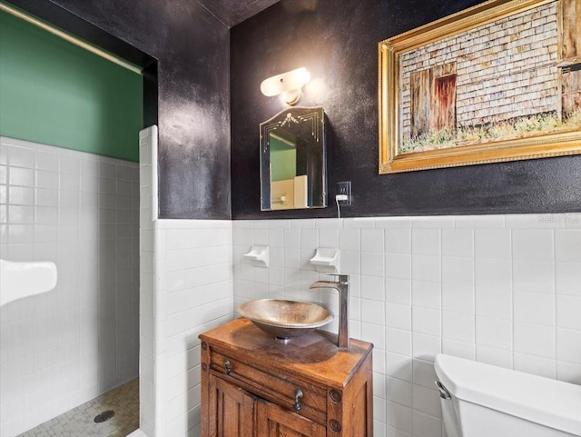 bathroom featuring vanity, toilet, tile walls, and a tile shower