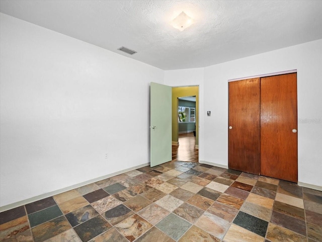 unfurnished bedroom with a textured ceiling and a closet