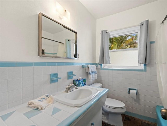 bathroom with vanity, toilet, and tile walls