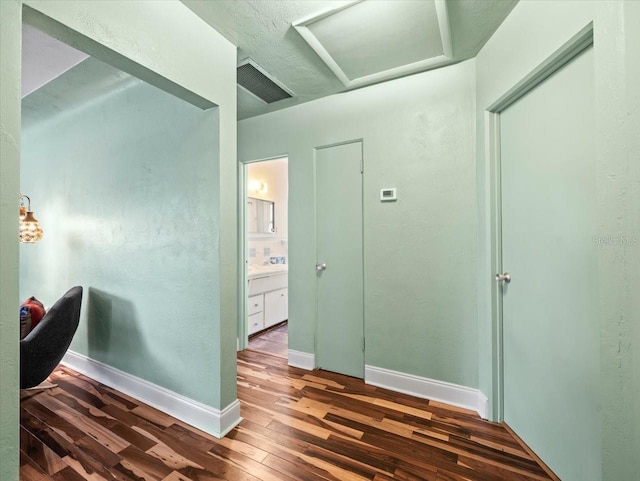 interior space featuring baseboards, attic access, wood-type flooring, and visible vents