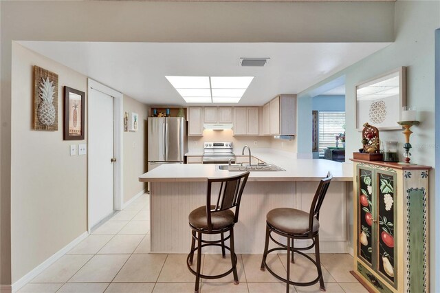 kitchen featuring kitchen peninsula, sink, appliances with stainless steel finishes, a kitchen breakfast bar, and light brown cabinets