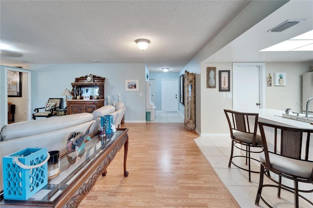 living room with a textured ceiling and light hardwood / wood-style flooring