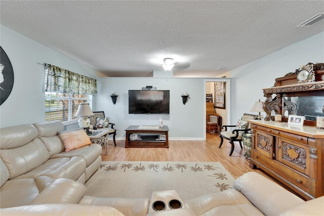 living room with a textured ceiling and light wood-type flooring