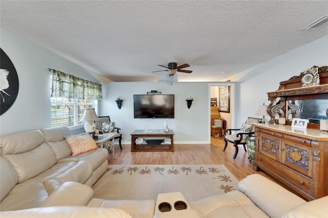 living room with ceiling fan, a textured ceiling, and light hardwood / wood-style flooring