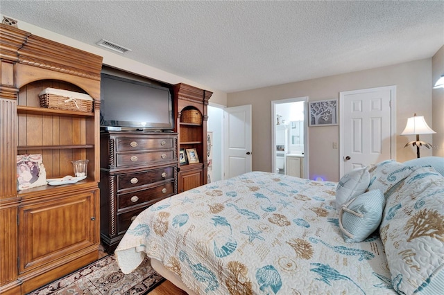 bedroom featuring a textured ceiling and ensuite bath