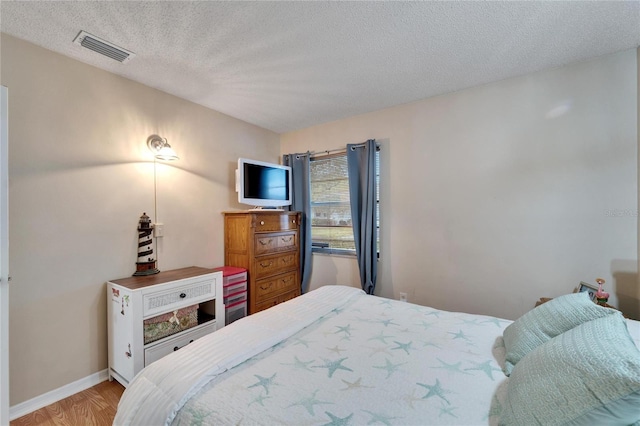 bedroom featuring a textured ceiling and light hardwood / wood-style floors